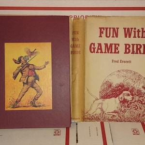 May include: A vintage hardcover book titled "Fun With Game Birds" by Fred Everett. The cover features a red and white illustration of a dog pointing at a bird in the grass.