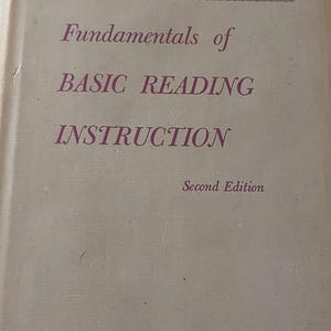 May include: Book cover with the title "Fundamentals of Basic Reading Instruction" in pink text. The book is a second edition and the authors are Mildred A. Dawson and Henry A. Bamman.