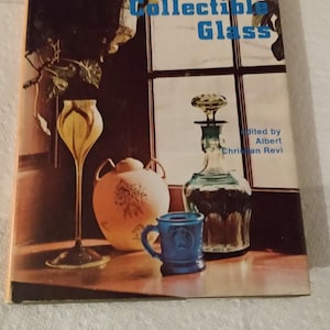 May include: A book titled "Collecting Glass" with a still life image of a yellow and white glass vase, a blue and white ceramic mug, a clear glass decanter with a green stopper, and a white ceramic jar with floral designs on a wooden table.