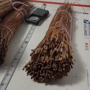 May include: Bundles of dried pine needles tied together with string. The needles are a light brown color and have a rough texture.