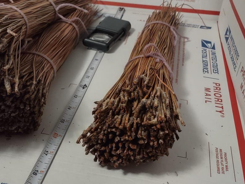 May include: Bundles of dried pine needles tied together with string. The needles are a light brown color and have a rough texture.