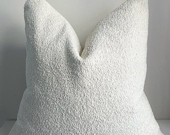 May include: A white, fluffy pillow with a textured surface. The pillow is made of a soft, plush material and has a simple, elegant design.