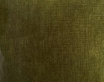 May include: Close-up of a square, olive-green textured fabric. The fabric has a soft, plush appearance with a subtle sheen. The colour is a deep, earthy tone, suitable for home decor items like cushions or upholstery.