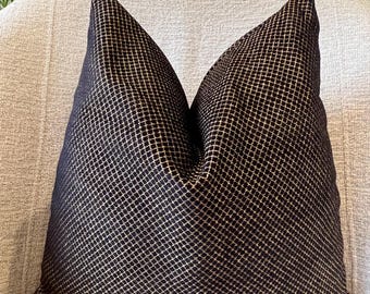 May include: A black and gold patterned throw pillow with a geometric design. The pillow is on a light gray couch.