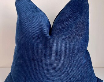 May include: A deep blue throw pillow with a textured fabric. The pillow is square shaped and has a simple design.