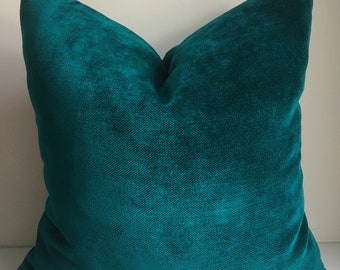 May include: A teal blue velvet pillow with a soft, textured surface.