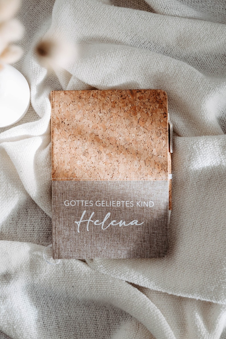 May include: A cork and linen journal with the text "Gottes geliebtes Kind" and the name "Helena" written in white.