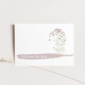 Könnte beinhalten: Eine weiße Karte mit einer Aquarell-Illustration eines Straußes rosa Blumen und grüner Blätter. Die Karte hat einen hellrosa Pinselstrich am unteren Rand mit dem Text "Ich bete für dich" in weiß.
