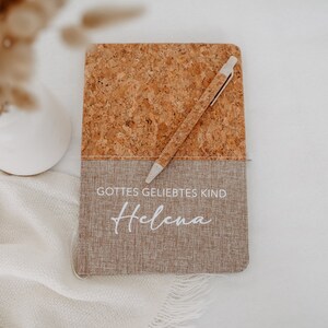 May include: A cork and linen journal with a white pen and the text "Gottes geliebtes Kind Helena" in white lettering.