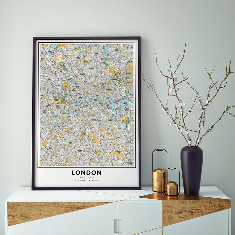 Peut inclure: Une impression encadr&eacute;e noire d'une carte de Londres, en Angleterre. La carte est de style vintage avec des lignes jaunes et grises. L'impression est accroch&eacute;e &agrave; un mur blanc au-dessus d'une commode dor&eacute;e et blanche.