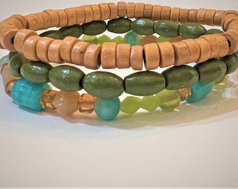 Può includere: Tre braccialetti sovrapposti realizzati con perline di legno di colore marrone, verde e turchese. Lo strato superiore è realizzato con perline di legno marrone, lo strato intermedio è realizzato con perline di legno verde e lo strato inferiore è realizzato con perline turchesi e marrone chiaro.