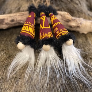 May include: Three gnomes with burgundy and gold hats. The hats are decorated with the text "Washington" and "Command".