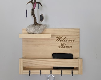 Può includere: Porta chiavi in legno con un ripiano e ganci. Il ripiano ha un piccolo albero di cristallo con pietre di agata appese ai rami. Il porta chiavi ha le parole "Welcome Home" incise sul davanti.