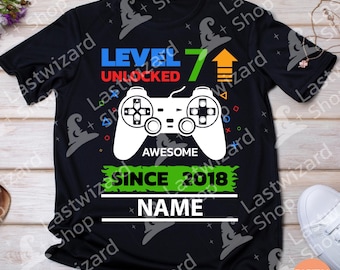 May include: Black t-shirt with a green, blue, and red video game controller graphic. The text "Level 7 Unlocked Awesome Since 2018" is printed on the shirt. The text "Name" is printed below the graphic.