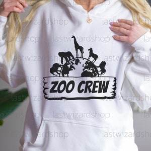 Pu&ograve; includere: Felpa bianca con una grafica nera di un globo terrestre circondato da animali e il testo "Zoo Crew" su un cartello di legno.