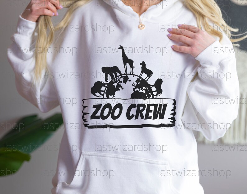 Pu&ograve; includere: Felpa bianca con una grafica nera di un globo terrestre circondato da animali e il testo "Zoo Crew" su un cartello di legno.