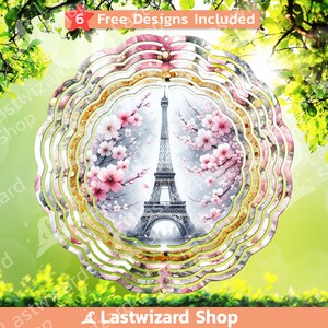 May include: A metal wind spinner with a design of the Eiffel Tower in Paris, France. The tower is surrounded by pink cherry blossoms and a light blue sky. The wind spinner has a gold glitter effect and is layered in a circular pattern.