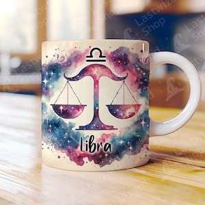 May include: White ceramic mug with a watercolor design of a Libra zodiac symbol with a galaxy background. The symbol is a scale with a galaxy design. The word "Libra" is written below the scale.