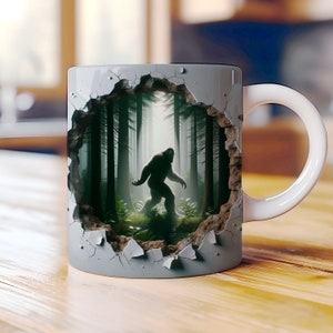 May include: A gray ceramic coffee mug with a 3D effect of a cracked wall revealing a forest scene with a silhouette of Bigfoot walking through the trees.