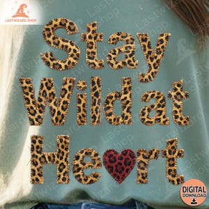 Può includere: Grafica turchese con la scritta "Stay Wild at Heart" in un font animalier. Un cuore rosso con stampa leopardata in basso. L'immagine include anche il testo "DIGITAL DOWNLOAD" e il nome del negozio "LASTWIZARD SHOP".