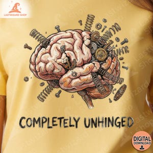 Pode incluir: Camiseta amarela com uma ilustração detalhada de um cérebro com engrenagens, molas e parafusos, e o texto "COMPLETELY UNHINGED" em preto. O logotipo Lastwizard Shop está no canto superior esquerdo. Um ícone de download digital está no canto inferior direito.