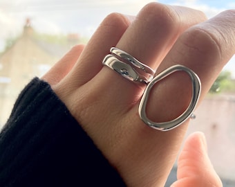 May include: A set of three silver rings, one with a simple oval shape and two stacked bands.