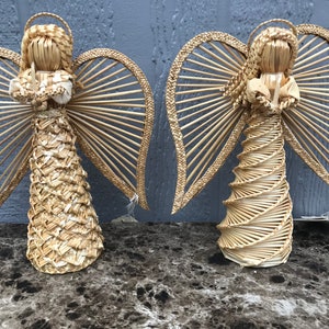 May include: Two straw angels with wings and a halo. The angels are made of woven straw and have a rustic, handmade look.
