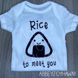 May include: White baby onesie with black text that reads "Rice to meet you". A black and white cartoon rice ball with a smiling face is above the text.