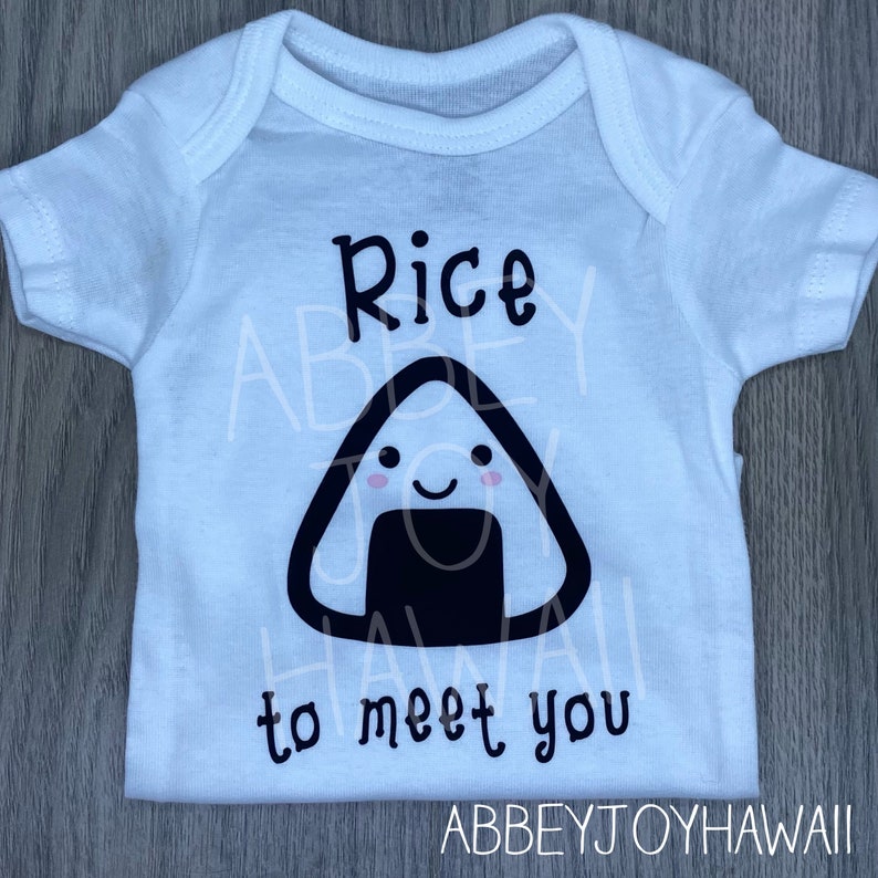 May include: White baby onesie with black text that reads "Rice to meet you". A black and white cartoon rice ball with a smiling face is above the text.