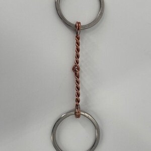 May include: A silver horse bit with a twisted copper center link. The bit has two round rings.