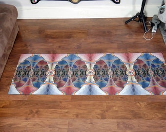 Op de afbeelding: Een kleurrijke yogamat met een geometrisch patroon in blauwe, rode en witte tinten. De mat heeft een herhalend ontwerp van gebogen lijnen en cirkels.