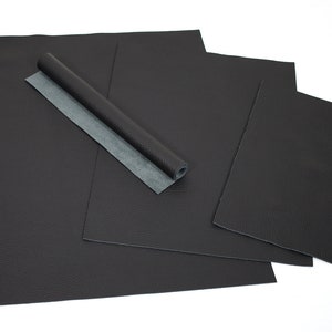 May include: Four pieces of black faux leather in various sizes, one rolled up, on a white background.