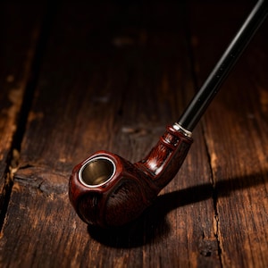 May include: A tobacco pipe featuring a dark reddish-brown wooden bowl with a textured, carved surface and a metallic silver-toned interior lining. The pipe includes a long, smooth, black stem that extends diagonally from the bowl.
