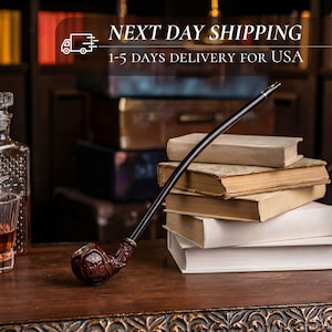 May include: A dark brown tobacco pipe with a curved stem rests on a wooden surface. The pipe has a detailed, textured bowl. The image also shows a stack of books and a bottle of liquor. The text in the image says "NEXT DAY SHIPPING" and "1-5 DAYS DELIVERY FOR USA".