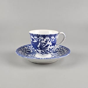 May include: A blue and white porcelain teacup and saucer set with a floral and bird design.