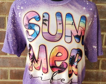 Puede incluir: Camiseta morada con un diseño de blanqueador blanco que dice "Summer Vibes" con palmeras y escenas de puesta de sol en las letras.