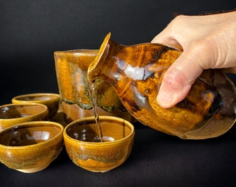 Handmade sake set with warmer, amber brown glazed sake set with gold speckles; 1 sake bottle with thumb indents, 4 sake cups & 1 sake warmer