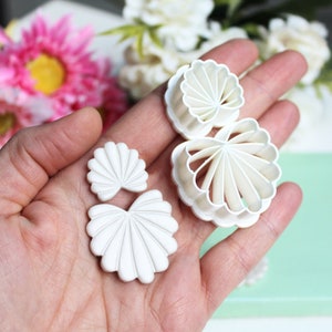 Könnte beinhalten: Ein Satz mit drei weißen Plastik-Ausstechern in Form von Blumen. Die Ausstecher haben die Form einer großen Blume, einer mittleren Blume und einer kleinen Blume.