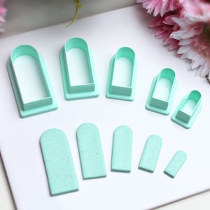 Może przedstawiać: Zestaw dziewięciu plastikowych foremek do ciasteczek w kolorze miętowo-zielonym, w różnych rozmiarach, w kształcie łukowatych prostokątów. Formy ułożone są na białym tle.