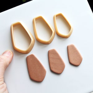 May include: Three pairs of polymer clay earrings in a geometric shape. The earrings are in two colors: a light brown and a darker brown. The earrings are displayed on a white surface.