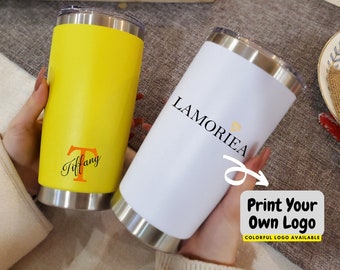 May include: Two stainless steel tumblers, one yellow and one white. The yellow tumbler has the name "Tiffany" written on it. The white tumbler has the text "LAMORIEA" printed on it. The white tumbler also has a sticker that says "Print Your Own Logo" with the text "COLORFUL LOGO AVAILABLE" underneath.