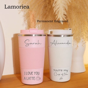 May include: Two personalized travel mugs with engraved names and sayings. The pink mug says "Sarah" and "I love you a latte" with a coffee cup icon. The white mug says "Alexanda" and "You're my cup of tea" with a teacup icon.