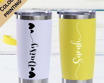 May include: Two stainless steel tumblers with personalized names. The tumbler on the left is white with black hearts and the name "Daisy". The tumbler on the right is yellow with the name "Sarah" in white.