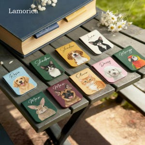 May include: A selection of magnetic bookmarks with pet portraits. The bookmarks feature dogs, cats, a rabbit, and a parrot, each with a name like "Rosie" or "Oliver." The bookmarks are in various colours and are displayed on a wooden surface.