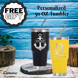 K&ouml;nnte beinhalten: Zwei personalisierte Becher mit 30 Unzen. Einer ist schwarz mit einem silbernen Anker und dem Namen "JACKSON" darauf. Der andere ist gelb mit einem Blumendesign und dem Namen "DANIEL" darauf.