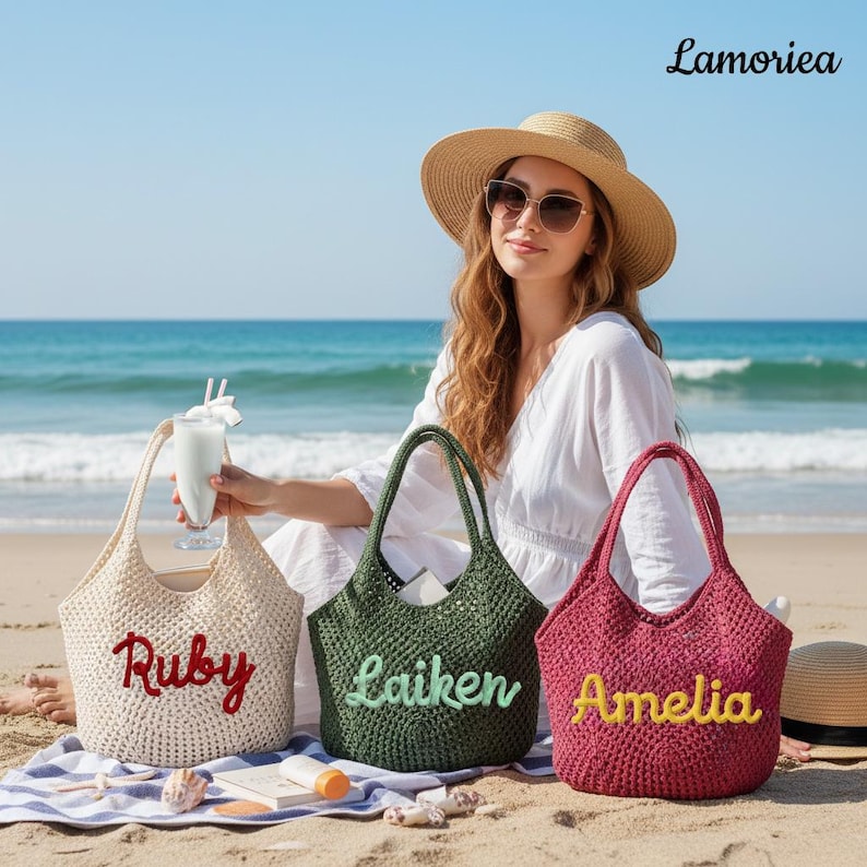 May include: Three crochet tote bags in cream, dark green, and magenta, each featuring a personalised name embroidered in cursive script: Ruby in red, Laiken in light green, and Amelia in yellow. The bags have open tops and woven textures.