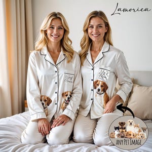Può includere: Set di pigiami avorio abbinati con finiture nere, con ritratti di cani e testo. Uno dice "Woof Mama", l'altro "Lily's Mom". Una grafica circolare mostra varie immagini di animali domestici. I pigiami sono abbottonati con una tasca.