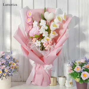 May include: A pink and white crocheted flower bouquet with a heart-shaped crocheted flower in the center. The bouquet is wrapped in pink tissue paper and tied with a white ribbon.