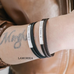 May include: Two black leather bracelets with silver metal plates. One plate has the text "& Baron" and the other has the Roman numeral "IV.XXVI".