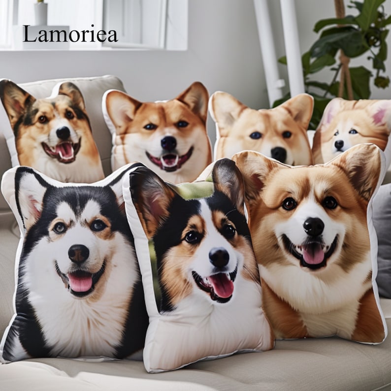 Puede incluir: Una colecci&oacute;n de cojines con forma de perro que representan varias razas, incluyendo Corgis y un Husky. Los cojines muestran caras de perros sonrientes y realistas en tonos marrones, negros y blancos. Los cojines est&aacute;n colocados en un sof&aacute; claro.